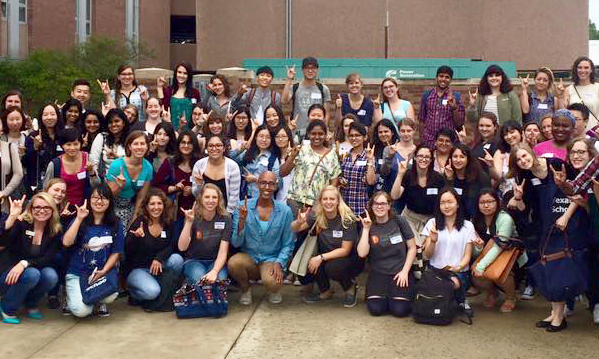 Outdoor group photo of iSchool students flashing the Hook 'em Horns hand sign