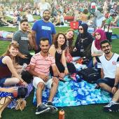 A group of international students sit on a picnic blanket