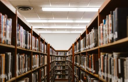 An long row of bookshelves under fluorescent lighting